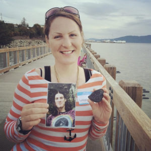 woman on bridge smiling holding picture of man